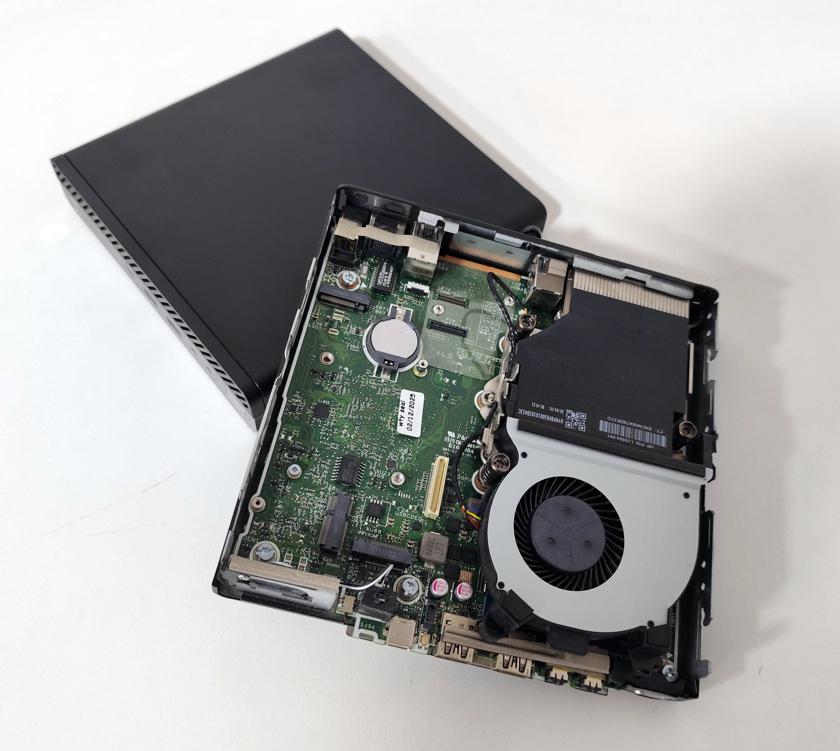 Open mini PC showing internal motherboard and cooling fan on white background, qalnexvori.shop